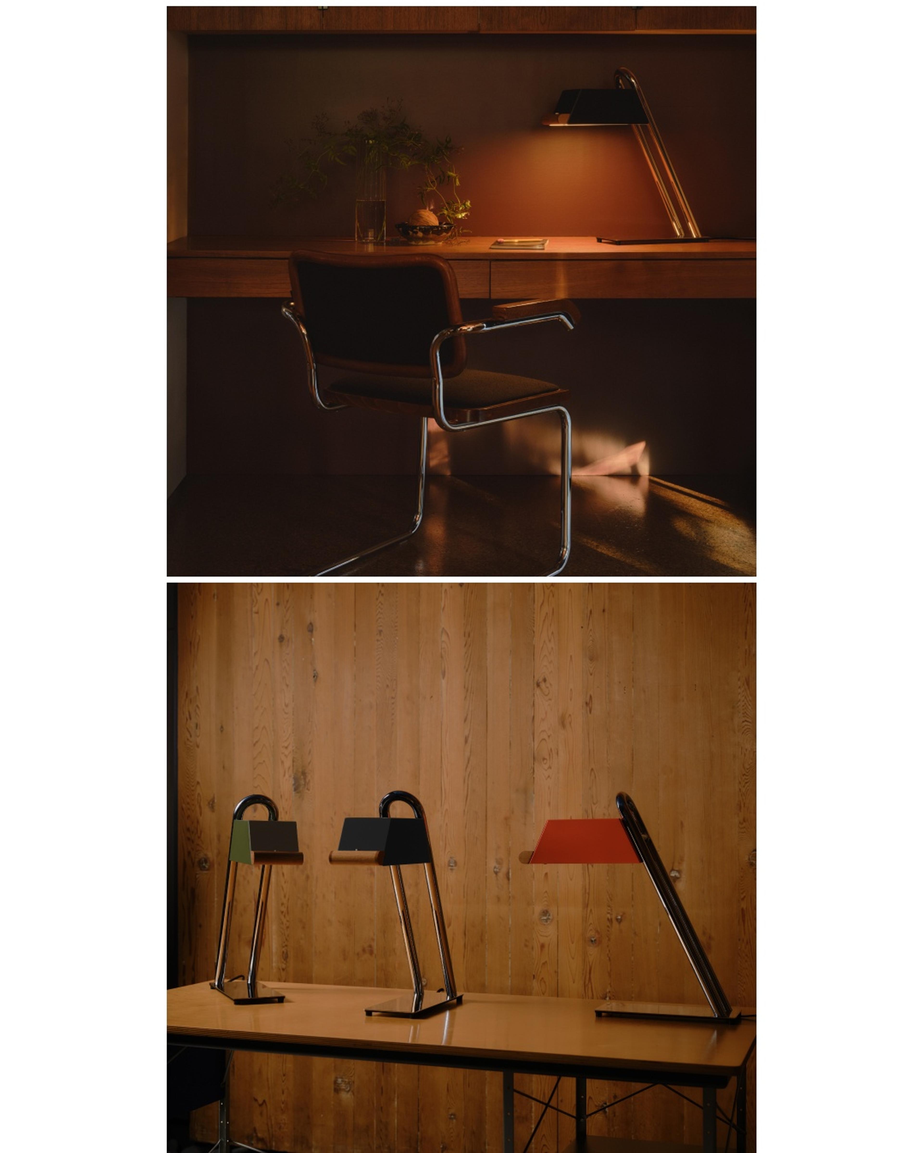 Dim-lit work station with wooden desk and mid century designed chair with metal and chrome table lamp lit