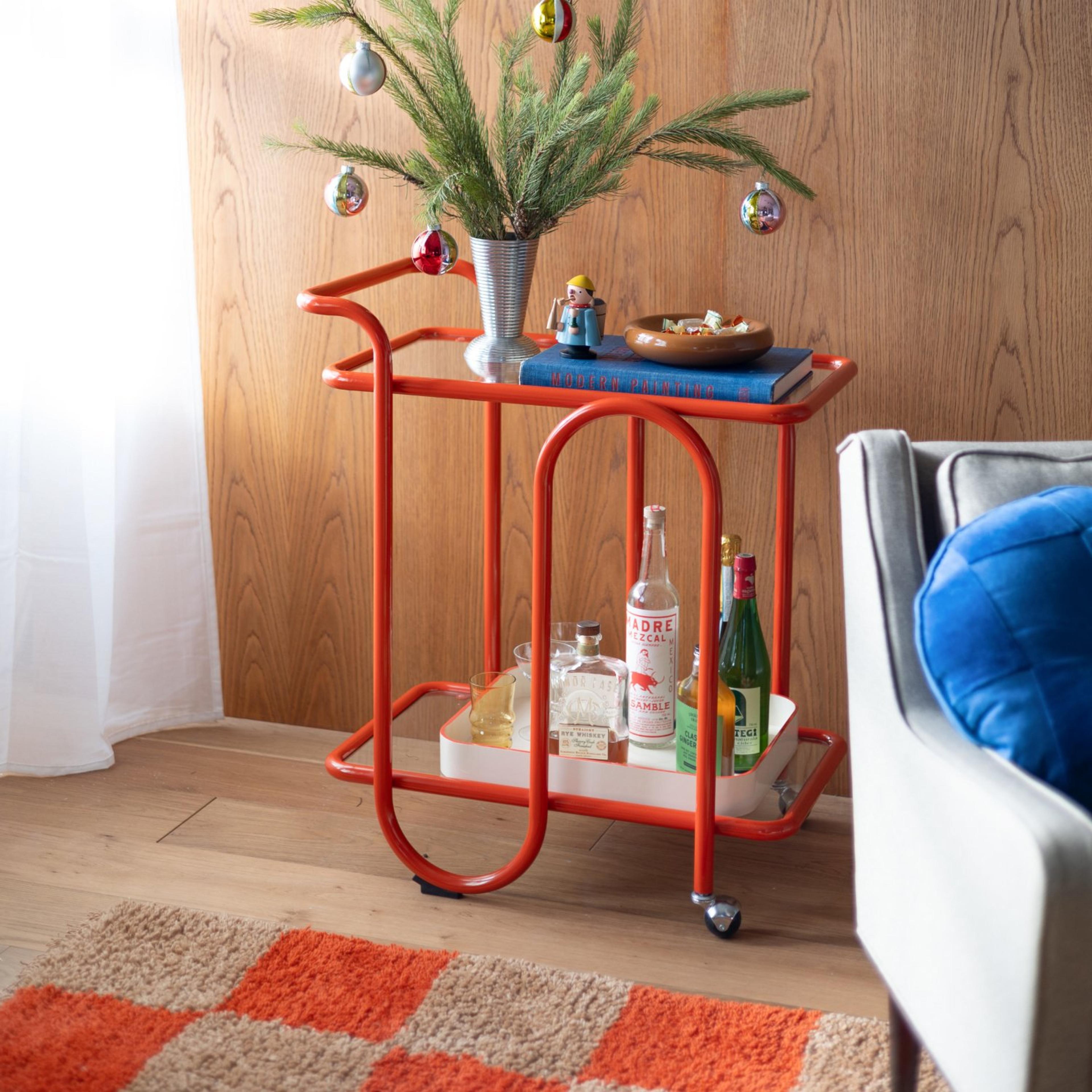 Red bar cart in living room with mini Christmas tree on top