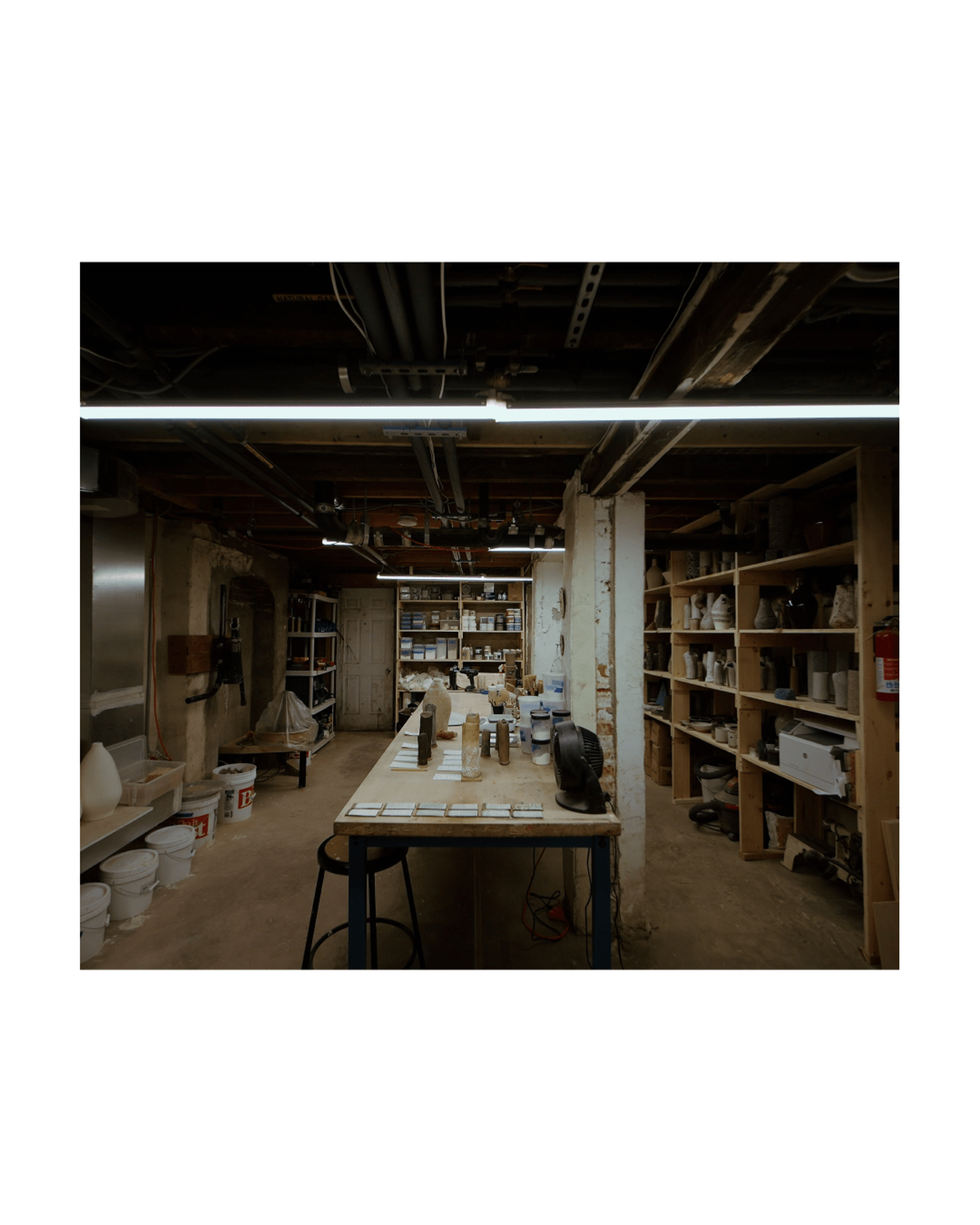 Basement ceramics studio with industrial overhead lighting