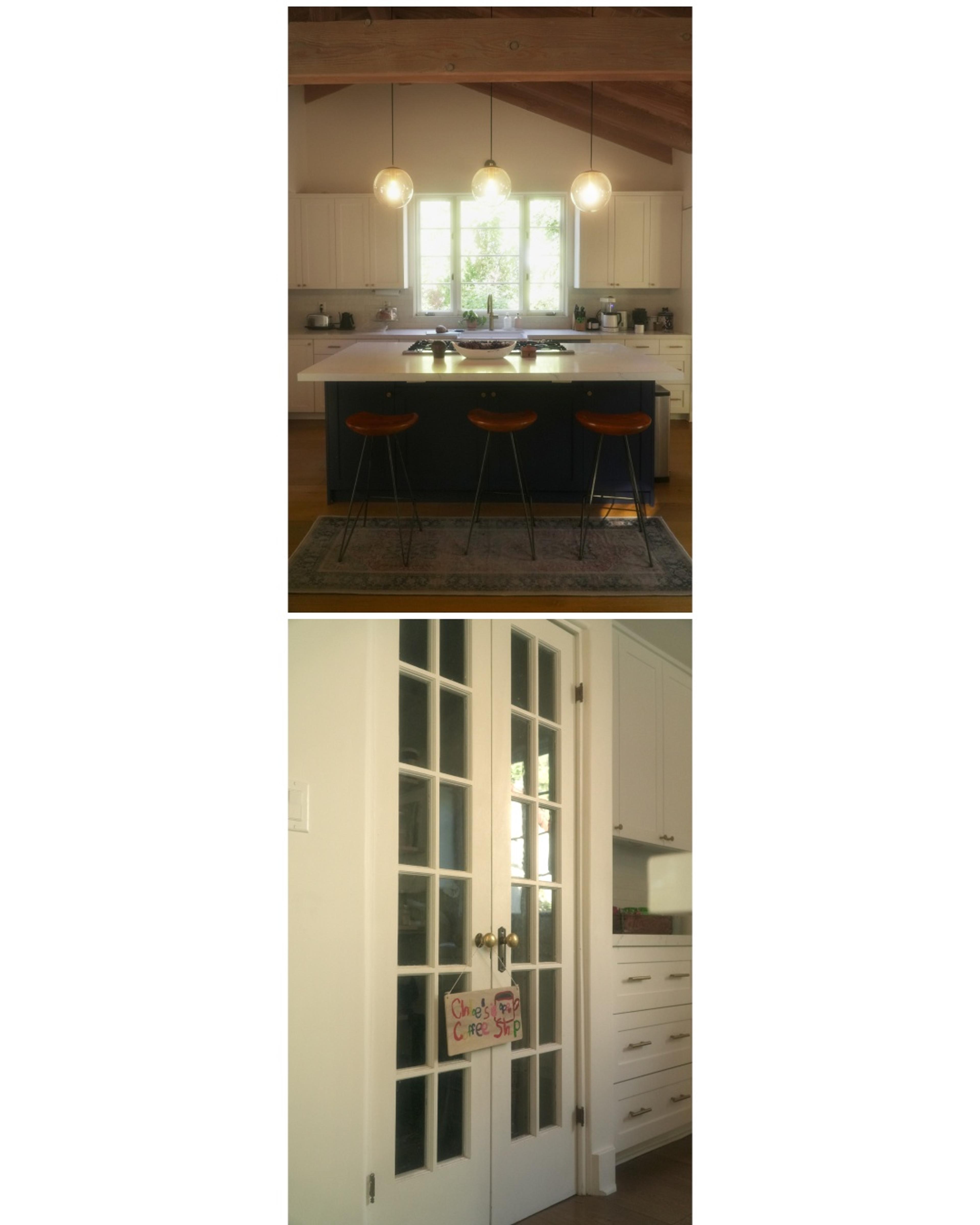 kitchen island with 3 pendants hanging over and white bay doors with sign that says "Chloe's coffee shop"