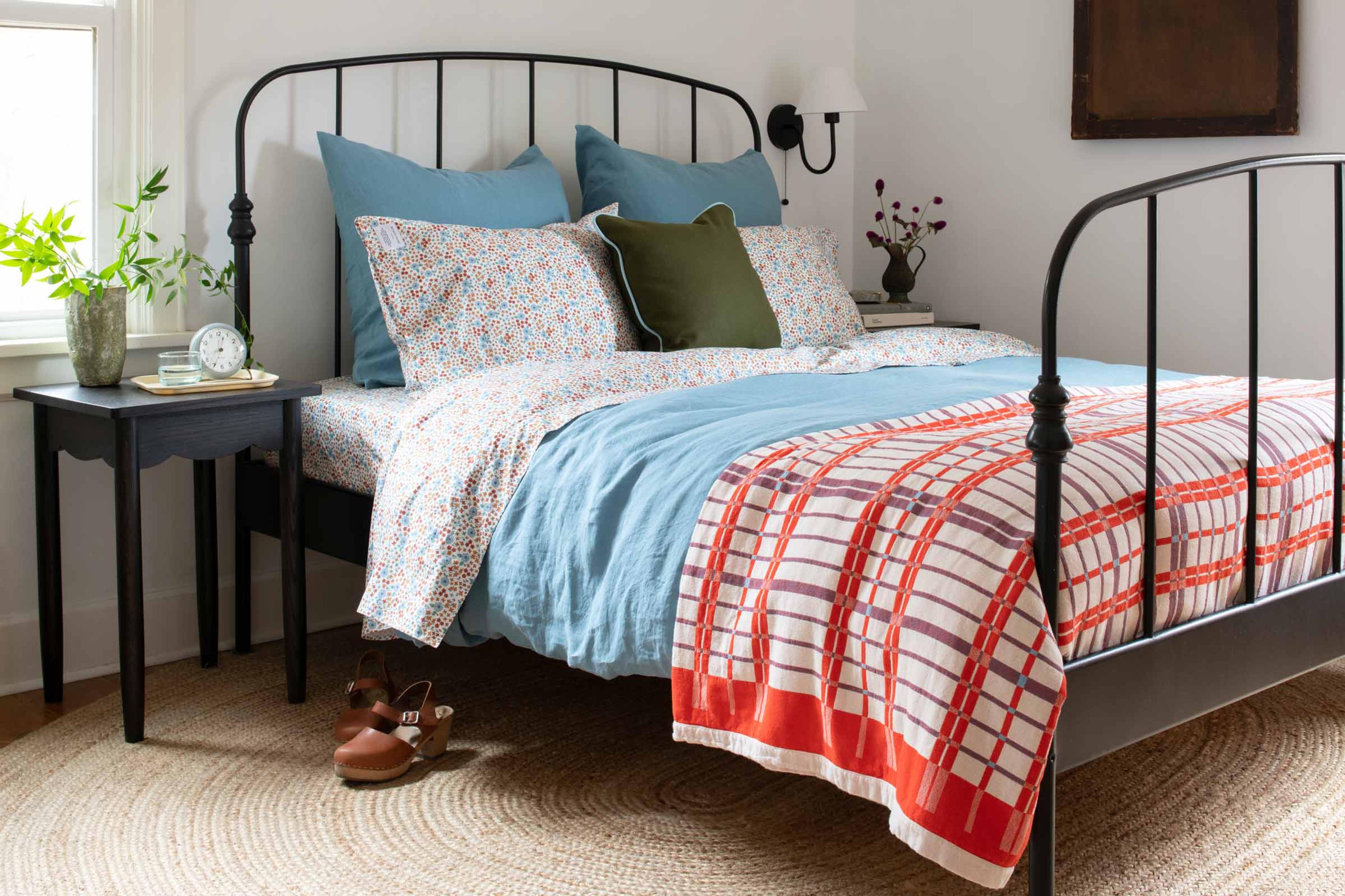 A cozy bed with floral bedding and a vintage-inspired quilt.