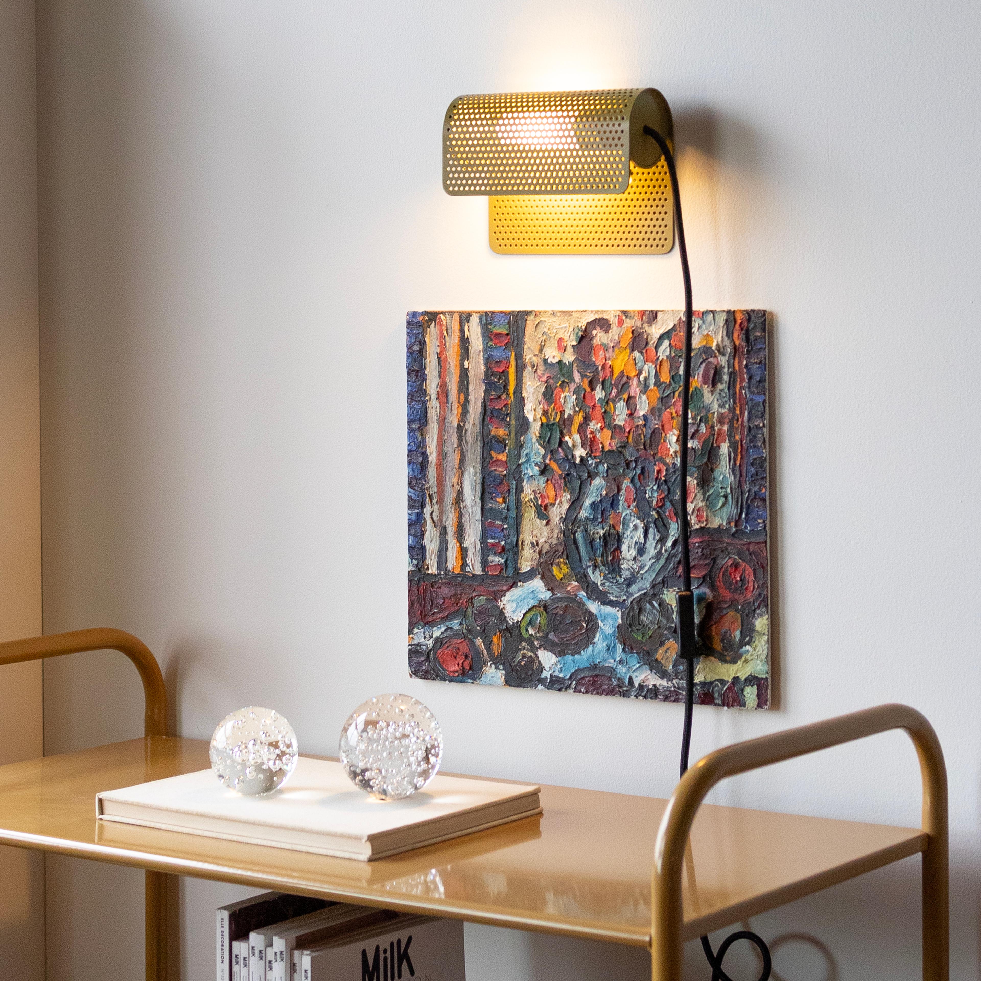 green perforated plug-in wall sconce over art
