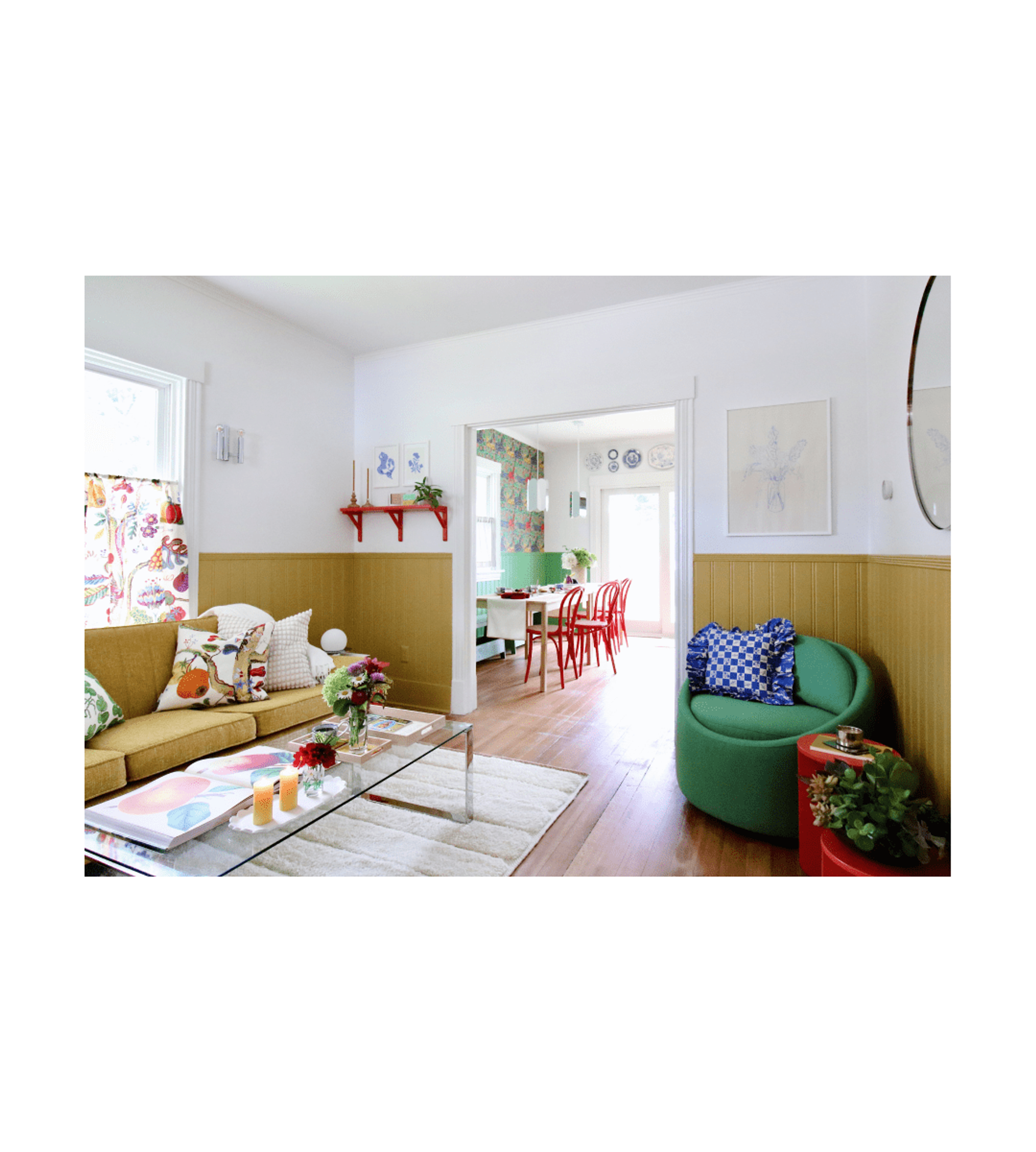 color filled living room looking into wallpapered dining room with red caned chairs