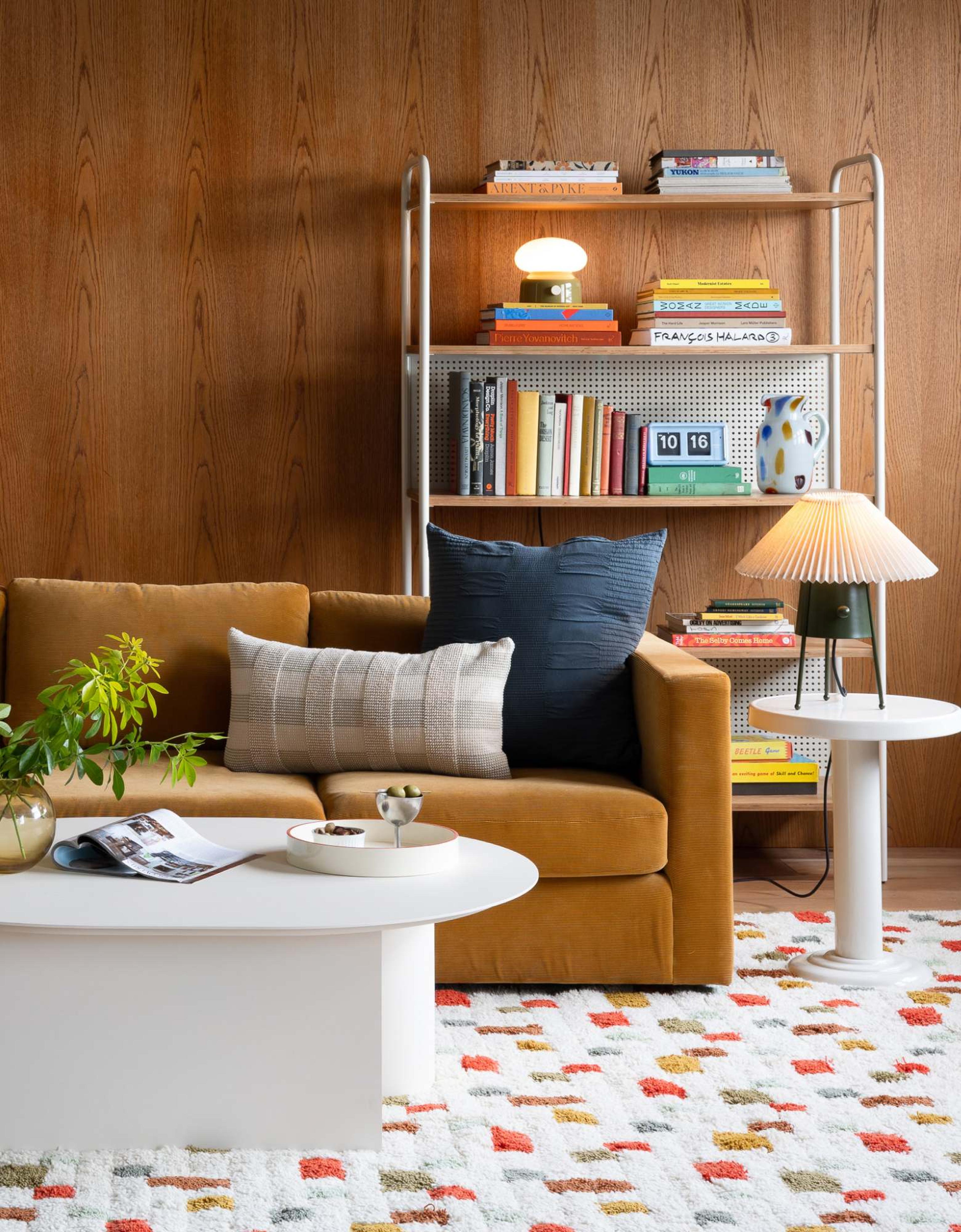 brown couch in wood wall living room surrounded by white accent furniture