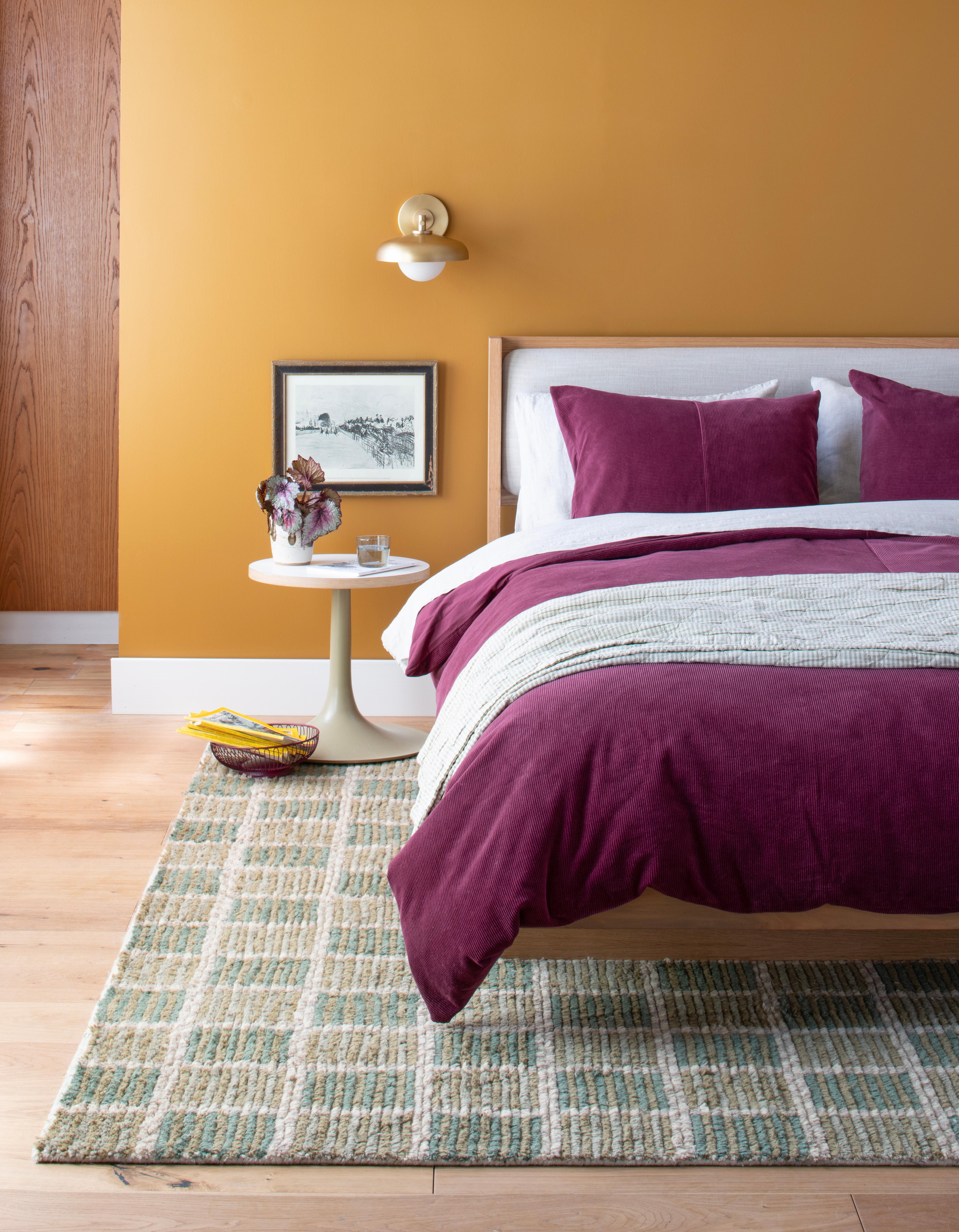 Bedroom with raisin colored duvet cover and side table with lamp