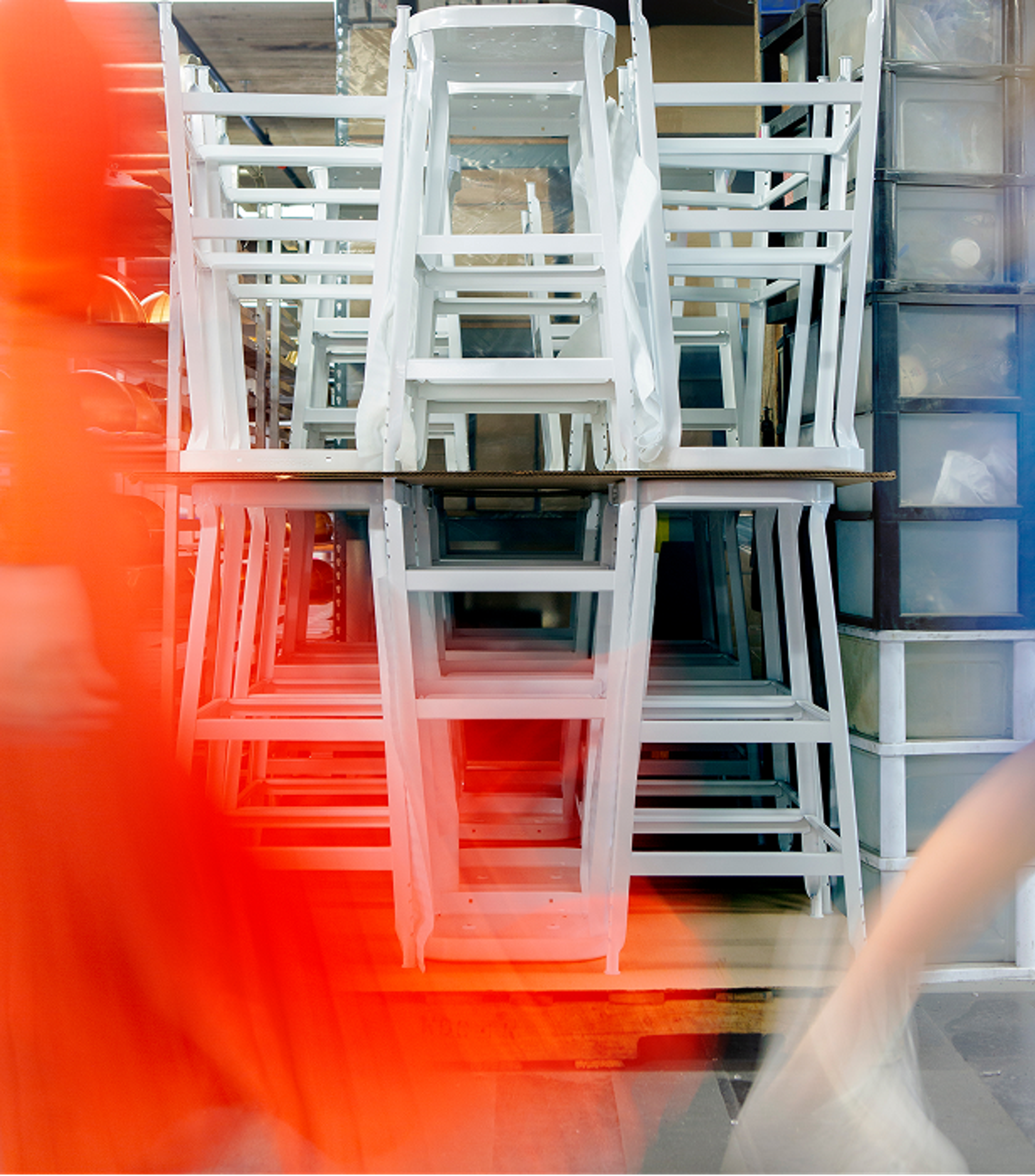 Artsy photo of white stools stacked on top of each other with red blur in front