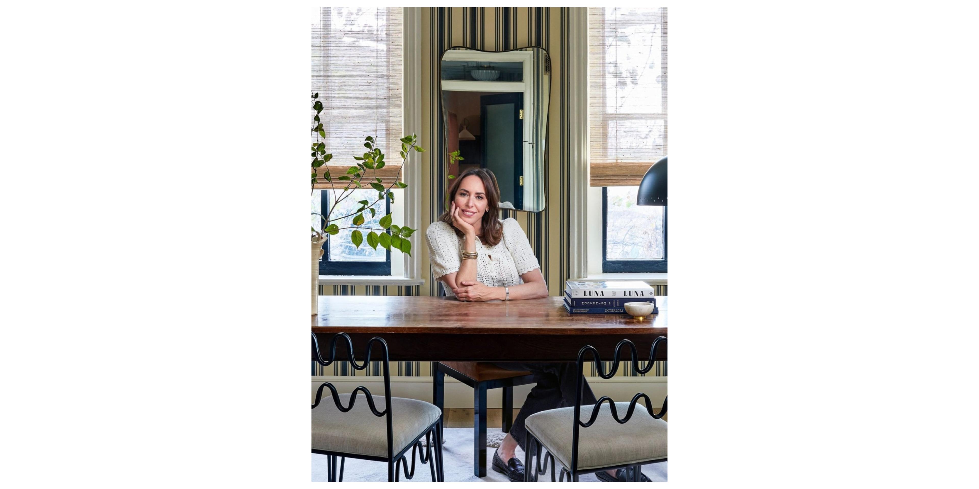 portrait of woman sitting behind desk resting chin in hand 