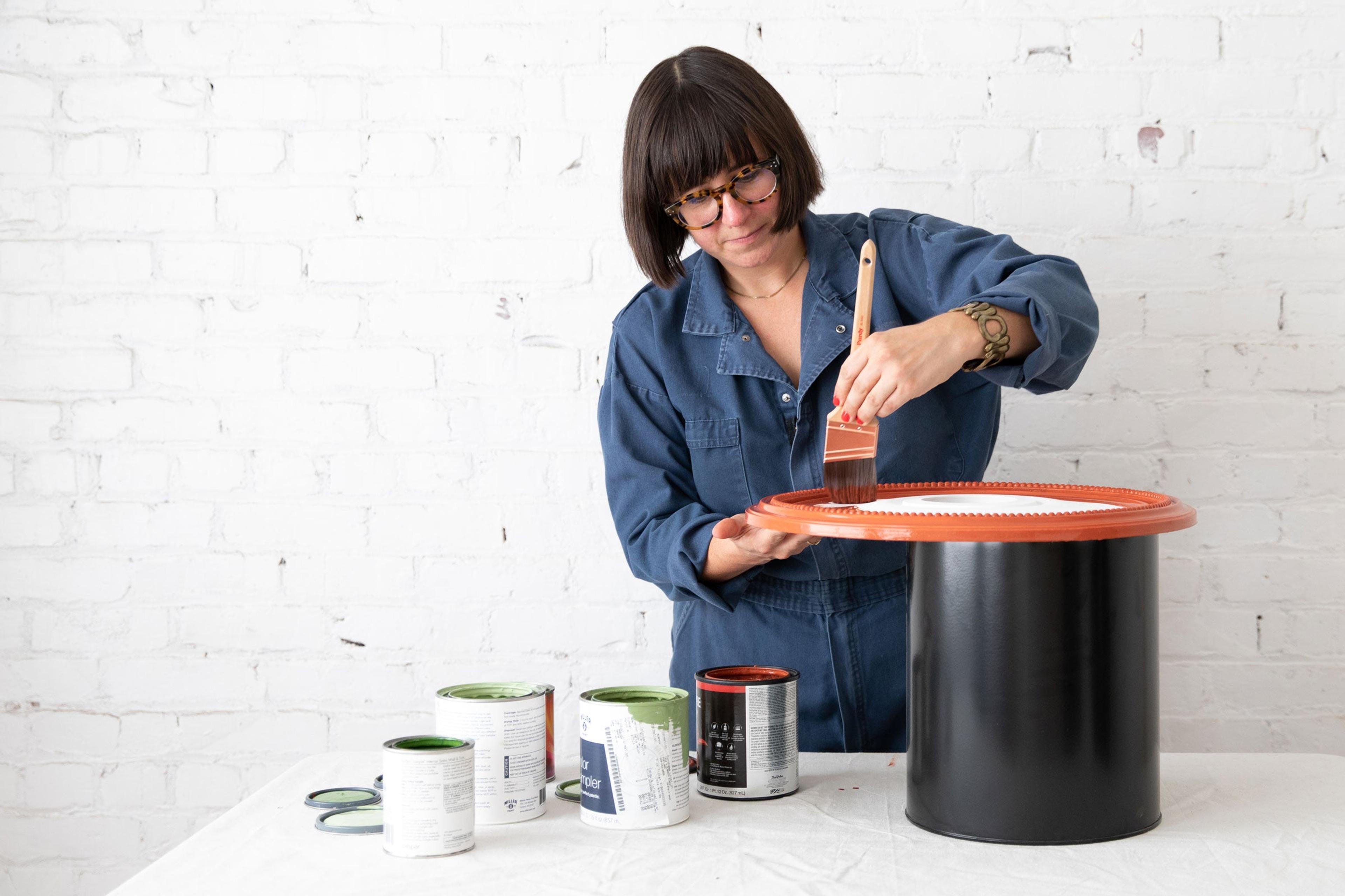 Jorie painting a ceiling medallion in an art studio.