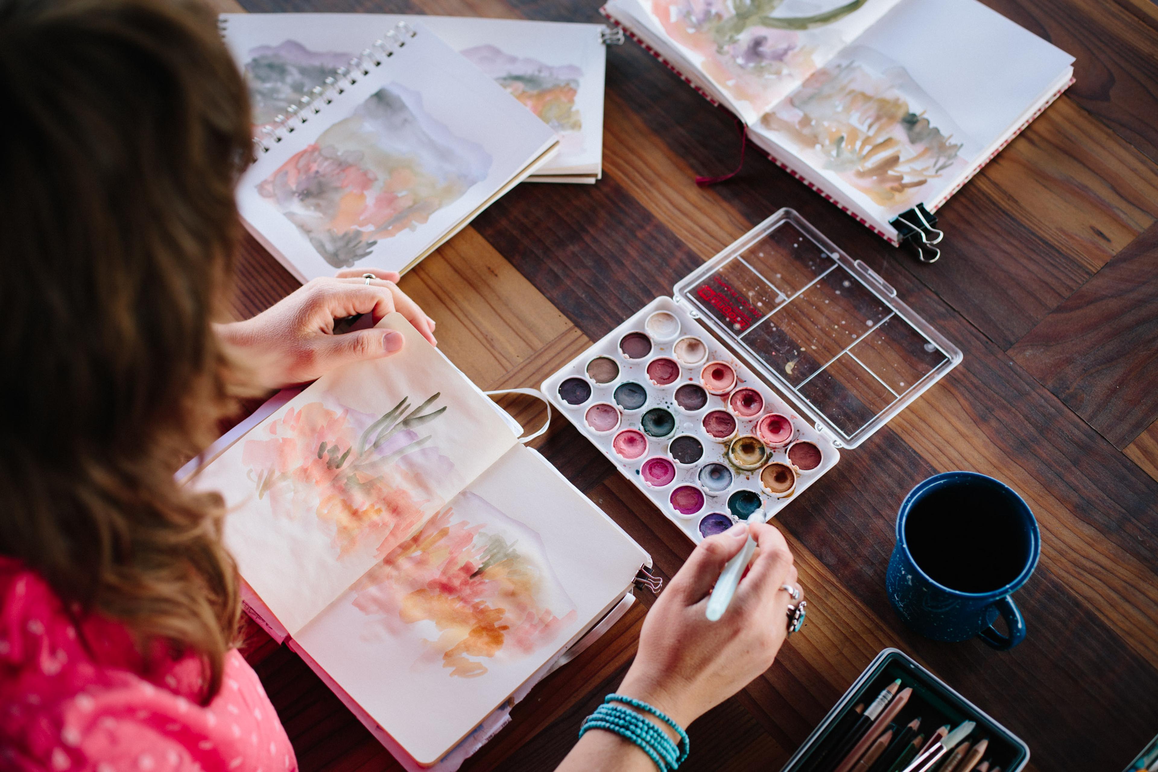 overhead of artist watercoloring in journal 