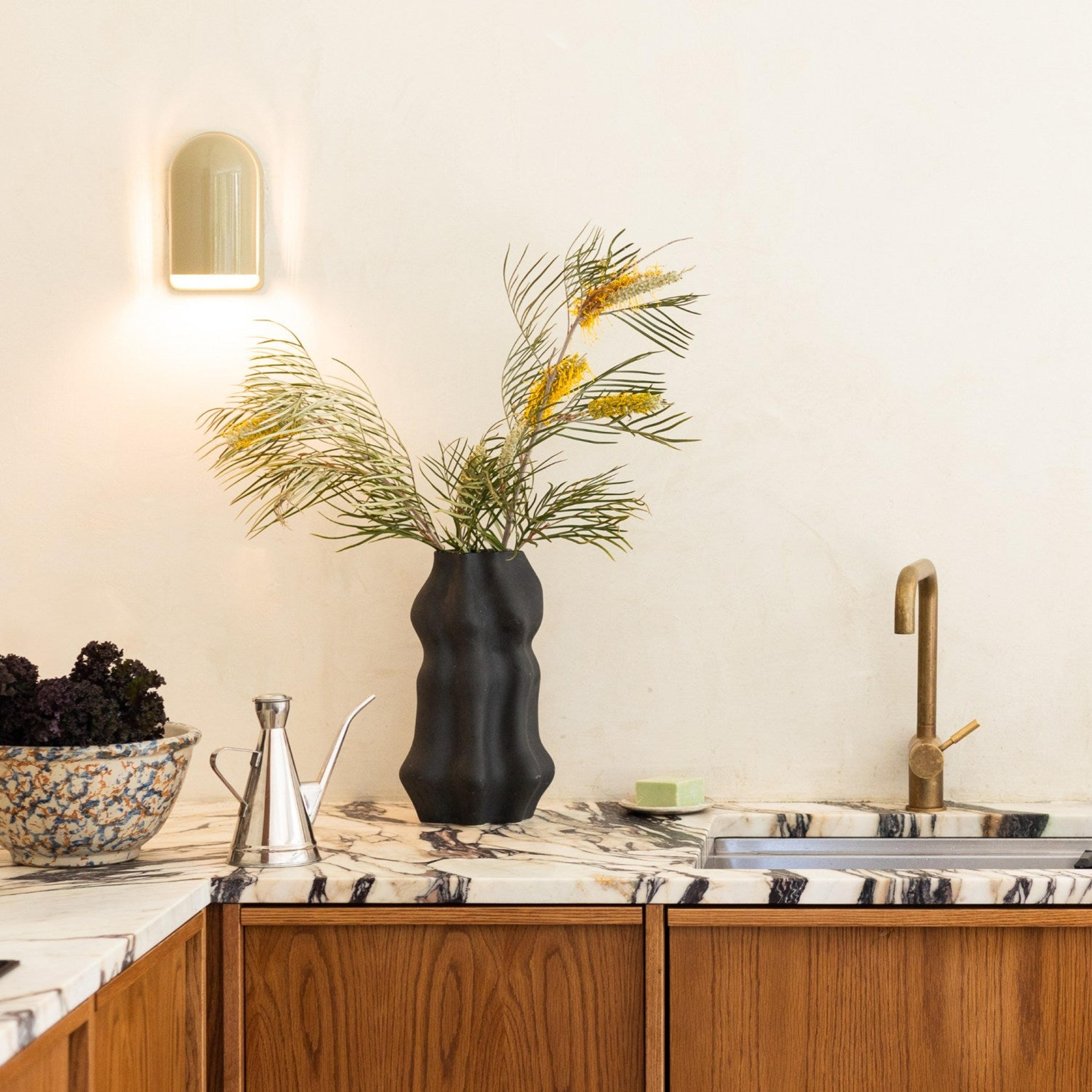 Wall sconce on white wall behind marble kitchen counter and sink