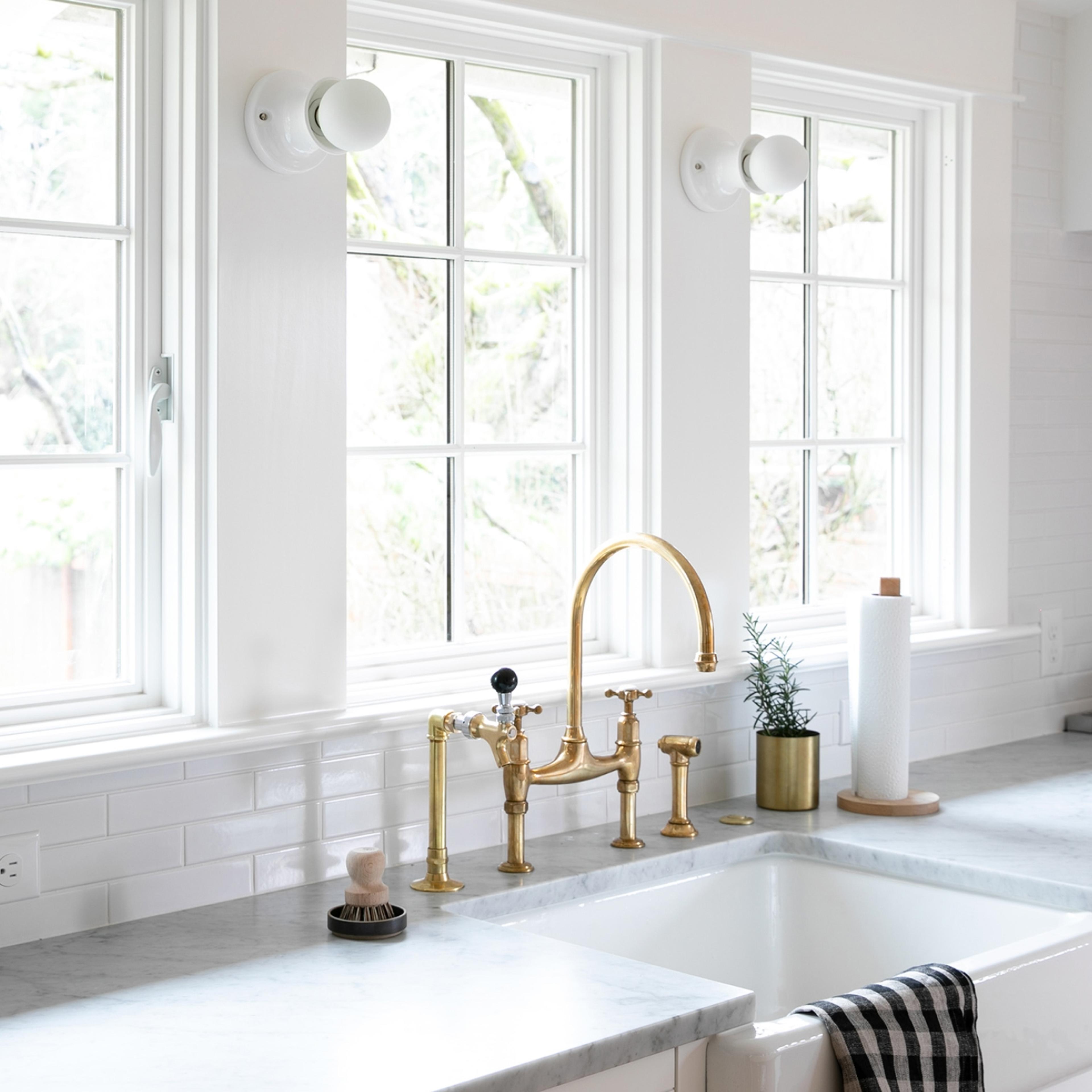 white kitchen windows and marble countertops with deep sink