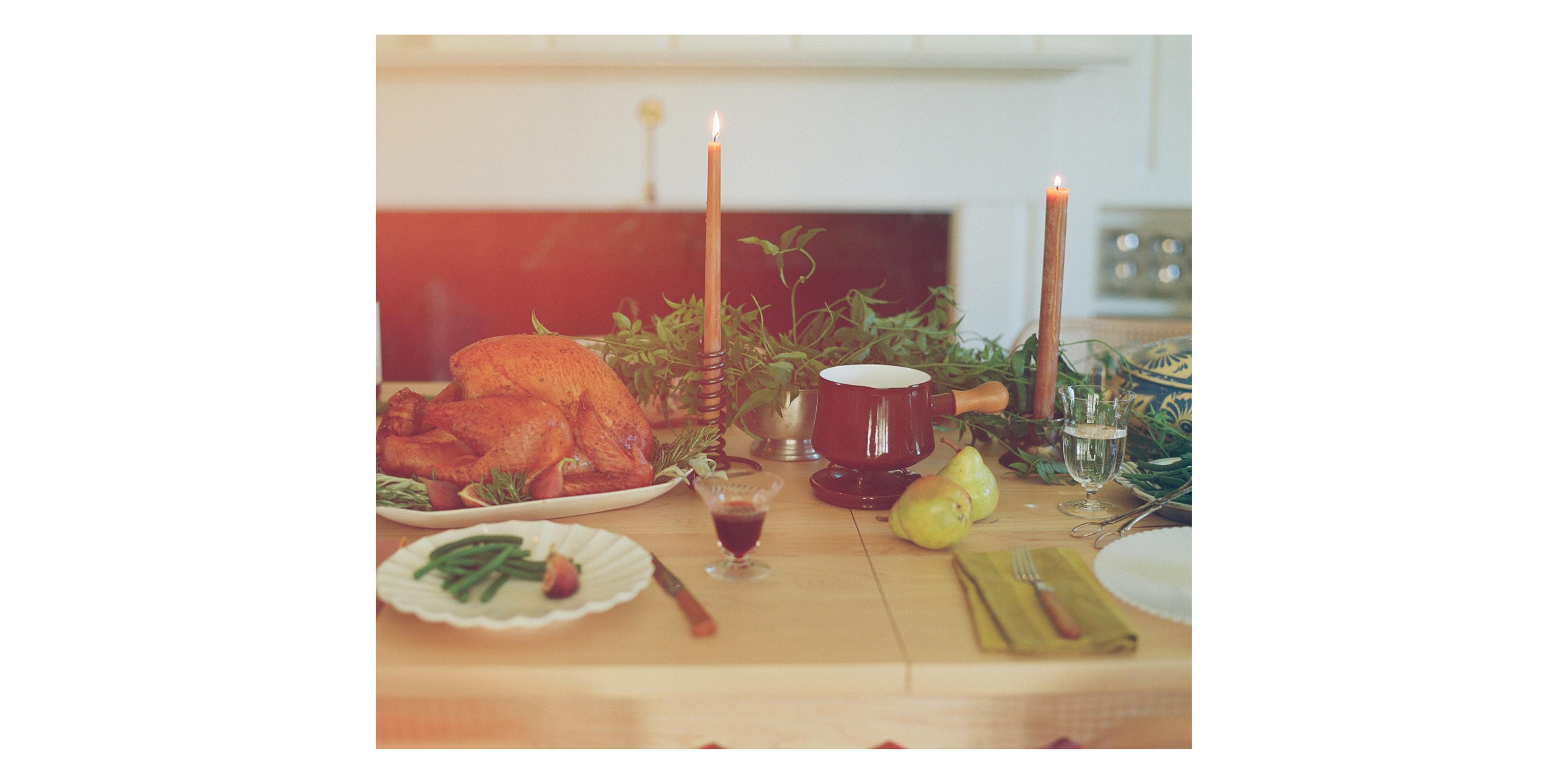 table with roasted turkey, lit candles and scalloped plates